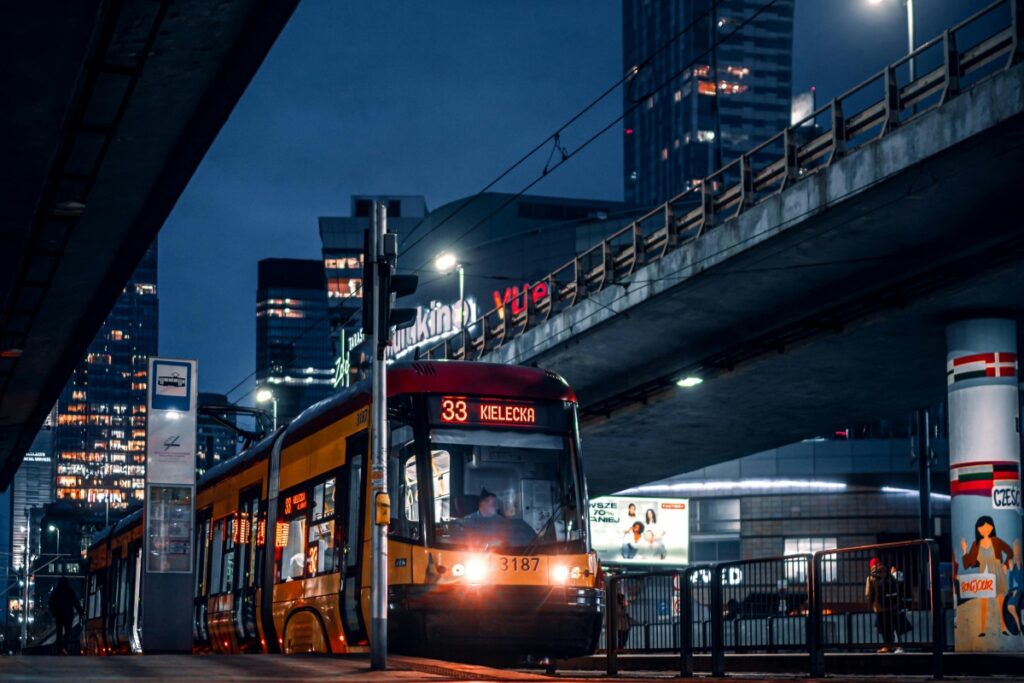 Obraz przedstawia tramwaj o numerze 33 z destinationem "Kielecka" w nocy w mieście, wokół high - riseów. Prognoza marketingu w mediach społecznościowych w Polsce na 2025 rok: kluczowe trendy i strategie dla marek wskazuje, że jak ten tramwaj przyciąga uwagę w urbanicznej scenerii, марки powinny stosować kreatywne podejścia, aby attrayować odbiorców w sieci.